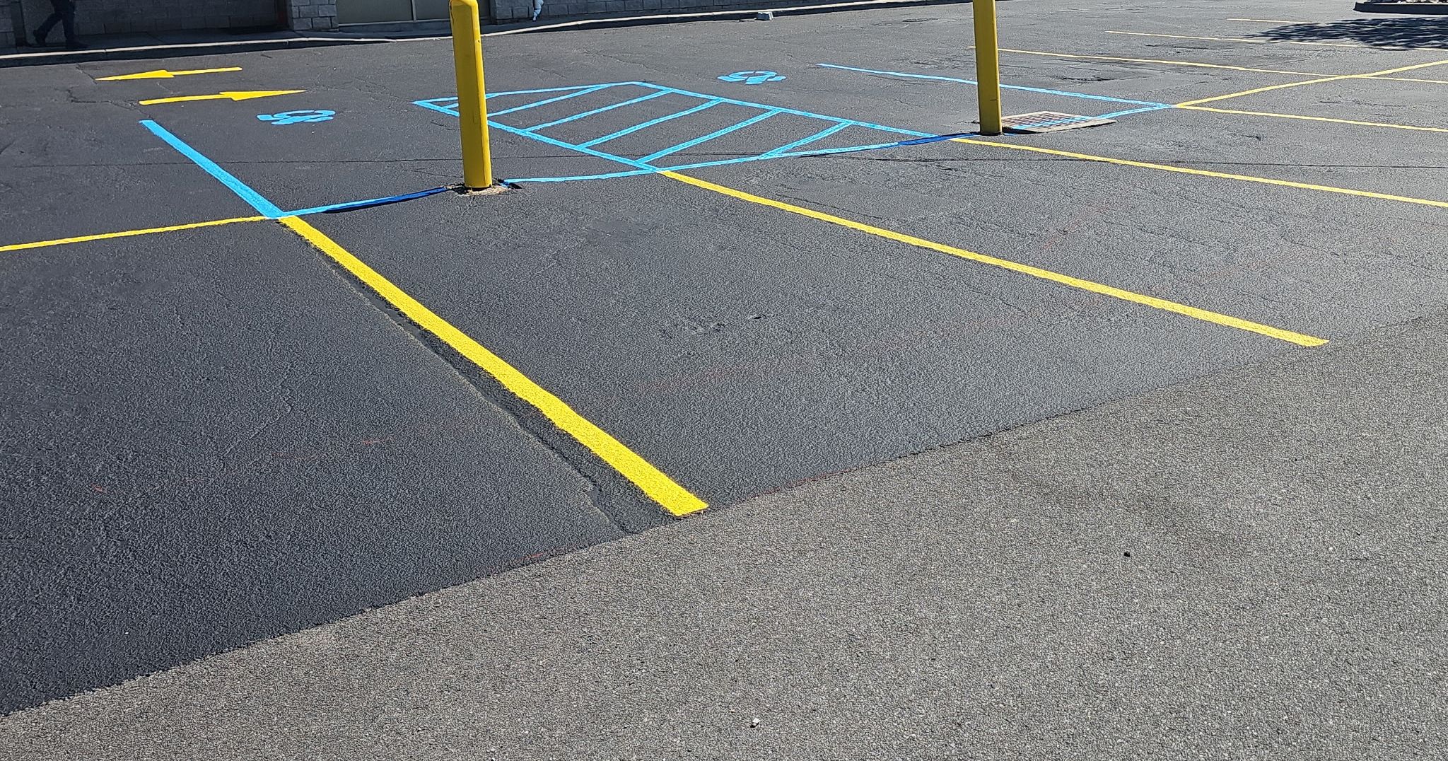 Freshly striped accessible parking stalls with blue ADA hatching and yellow lines