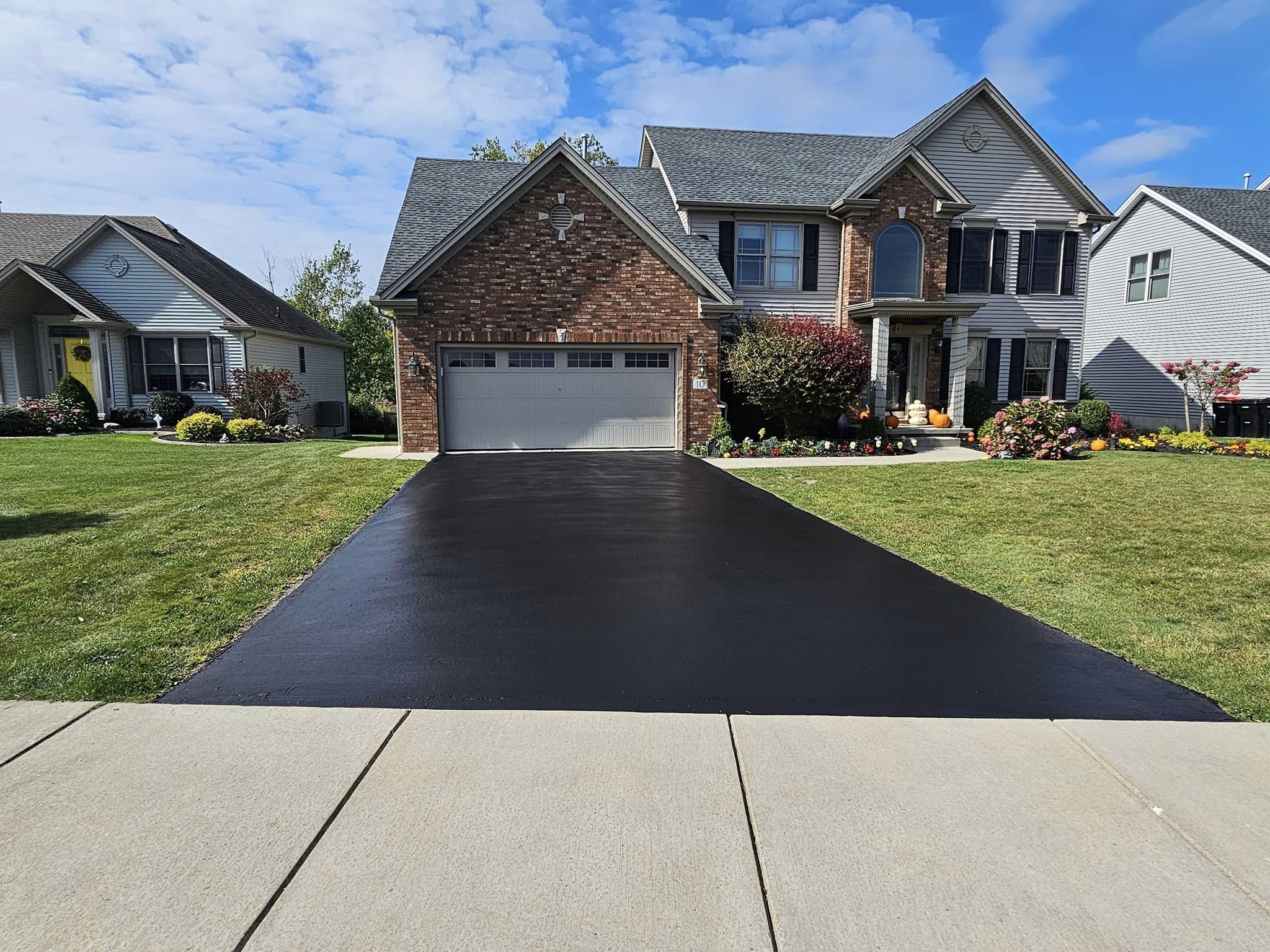 Brick estate home with a freshly sealed jet-black driveway