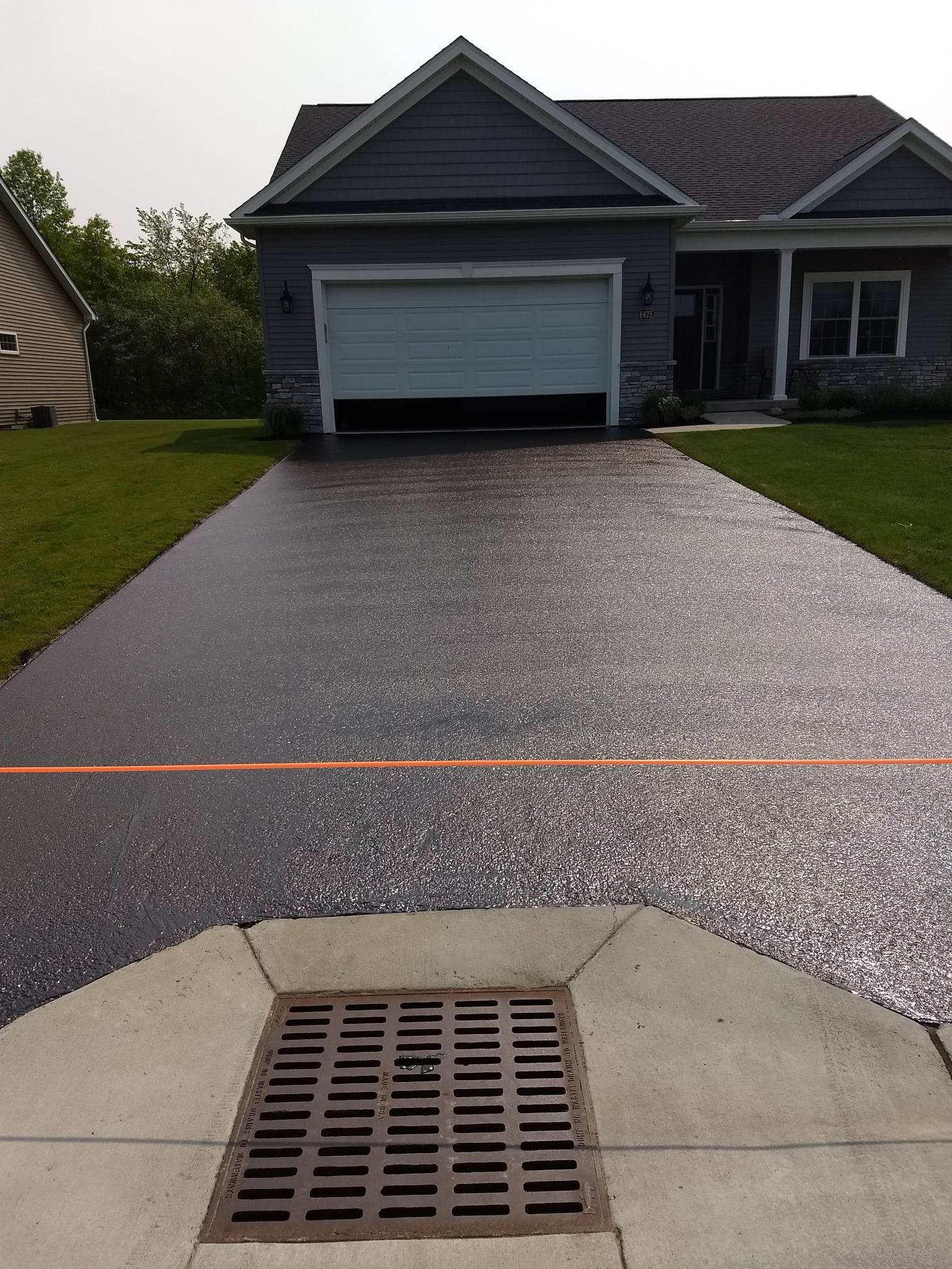 Modern gray house with a freshly sealed glossy driveway