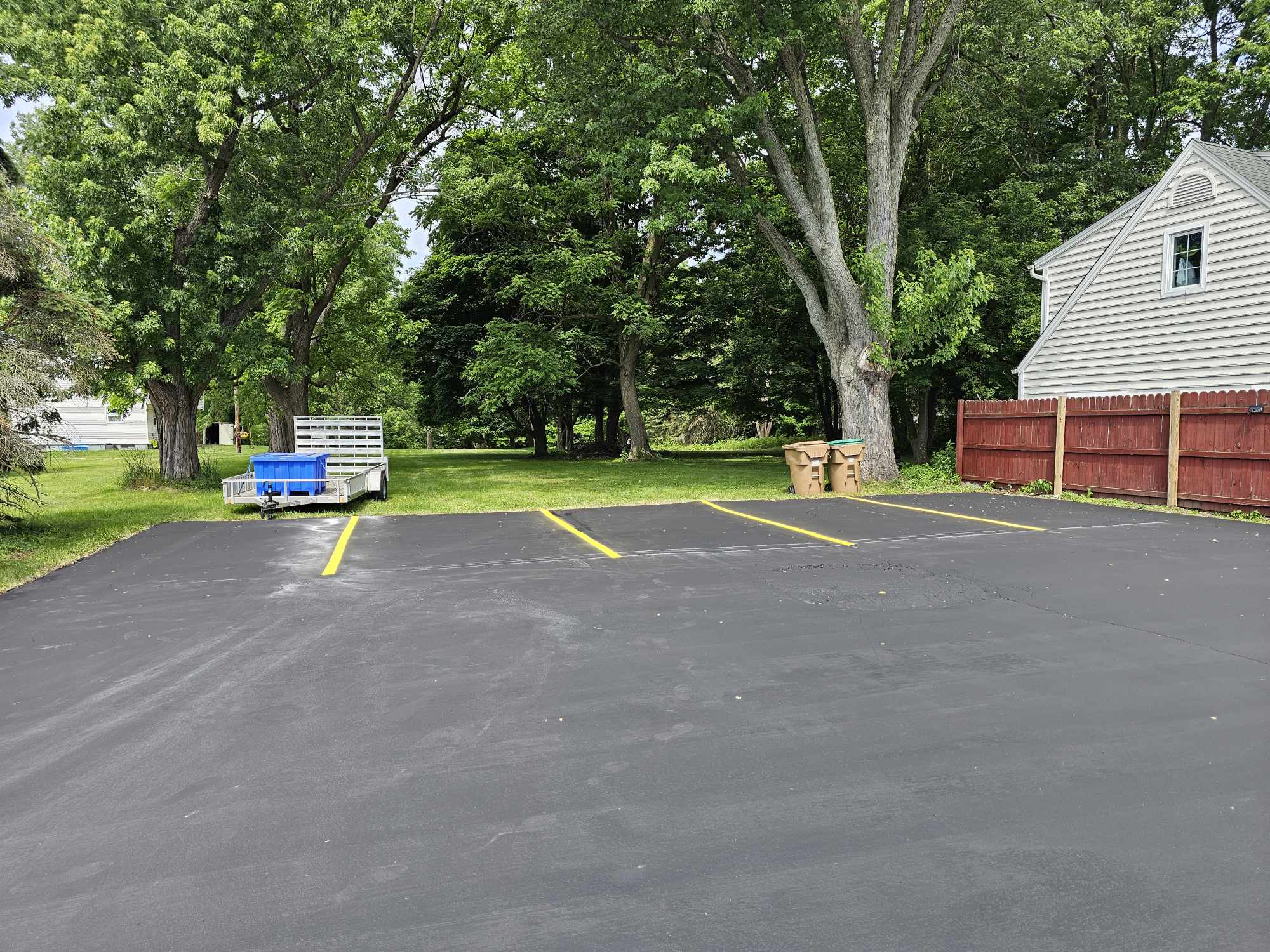 Residential parking pad with crisp yellow stalls and trees